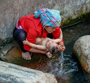 A mother bathing her baby in a river